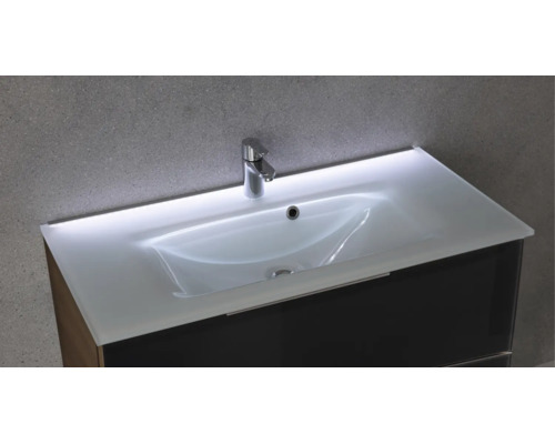 Lavabo en verre avec éclairage LED intégré, robinetterie chromée et meuble sous-vasque sombre.