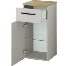 Meuble bas de salle de bain avec un tiroir et une porte, comprenant une étagère en verre et un plateau supérieur aspect bois.