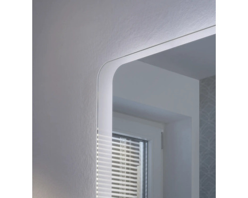 Gros plan d'un miroir de salle de bain avec éclairage LED intégré et coins arrondis.