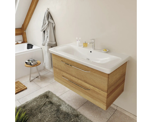 Meuble sous-lavabo moderne suspendu en aspect bois avec une large vasque blanche et des poignées chromées.