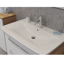 Meuble de salle de bains moderne avec lavabo en céramique blanche et robinet chromé sur un mur de carreaux gris.