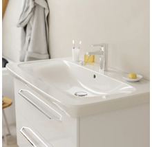 Meuble sous-vasque blanc moderne avec deux tiroirs, vasque intégrée en céramique et robinet chromé dans une salle de bain lumineuse.