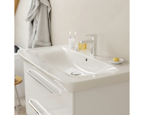Meuble sous-vasque blanc moderne avec deux tiroirs, vasque intégrée en céramique et robinet chromé dans une salle de bain lumineuse.