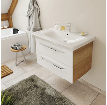 Meuble sous-vasque suspendu moderne avec tiroirs blancs, côtés en chêne et vasque en céramique dans une salle de bain lumineuse.