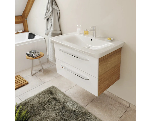 Meuble sous-vasque suspendu moderne avec tiroirs blancs, côtés en chêne et vasque en céramique dans une salle de bain lumineuse.