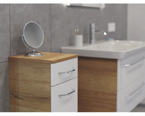 Meuble d'appoint de salle de bains moderne avec deux tiroirs blancs et corps en aspect bois à côté d'un lavabo avec miroir cosmétique.