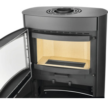 Poêle à bois noir avec porte ouverte, chambre de combustion avec briques réfractaires et grille, raccordement de fumée sur le dessus.