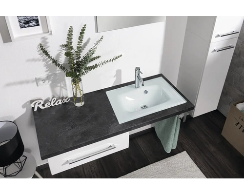Helles Badezimmer mit weissem Unterschrank, dunkler Arbeitsplatte in Steinoptik und integriertem weissem Waschbecken mit verchromter Armatur.