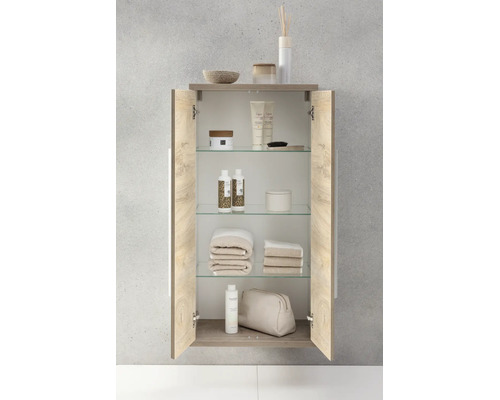 Armoire murale de salle de bains ouverte, aspect bois, avec étagères en verre, garnie de produits de soin et de serviettes.