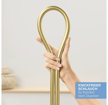 Eine Hand hält einen flexiblen, goldfarbenen Brauseschlauch, um die knickfreie Eigenschaft zu demonstrieren.