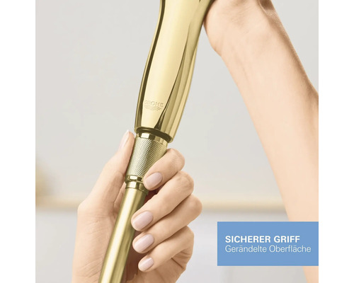 Goldfarbene ausziehbare Küchenbrause mit Grohe Logo und gerändelter Oberfläche für sicheren Halt, gehalten von zwei Händen.
