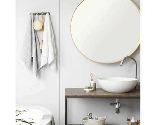 Modernes, helles Badezimmer mit rundem Spiegel, weissem Aufsatzwaschbecken auf Holzwaschtisch und Handtuchhalter mit Textilien.