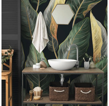Fototapete mit grossen botanischen Blättern im Badezimmer hinter einem Waschtisch aus Holz mit weissem Aufsatzwaschbecken und Zubehör.
