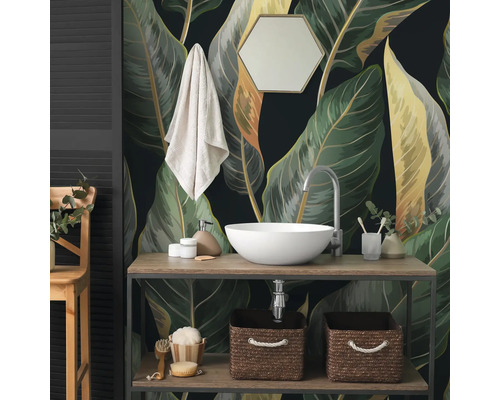 Fototapete mit grossen botanischen Blättern im Badezimmer hinter einem Waschtisch aus Holz mit weissem Aufsatzwaschbecken und Zubehör.