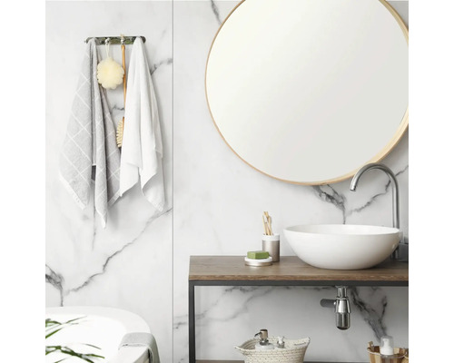 Salle de bains lumineuse avec mur en marbre blanc, miroir rond, vasque à poser en céramique blanche sur console en bois et robinet chromé.