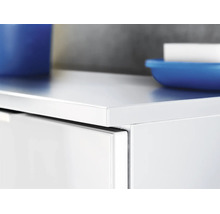 Gros plan sur un meuble de salle de bain blanc avec une surface lisse, un tiroir et des accessoires de salle de bain.