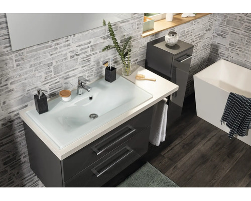 Modernes Badezimmer mit dunkelgrauem Waschtisch, Glaswaschbecken und quadratischer Badewanne vor Wänden in Steinoptik.