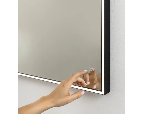 Miroir de salle de bains éclairé avec cadre noir et capteur tactile pour commander l'éclairage LED.