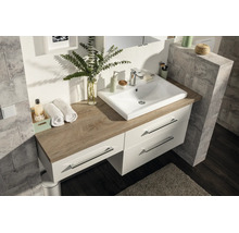 Meuble de salle de bain moderne avec vasque en céramique blanche sur un plan de toilette aspect chêne. Meuble bas avec trois tiroirs.