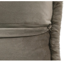 Gros plan d'un coussin en velours taupe avec une fermeture éclair invisible et un bord en fausse fourrure.