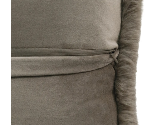 Gros plan d'un coussin en velours taupe avec une fermeture éclair invisible et un bord en fausse fourrure.