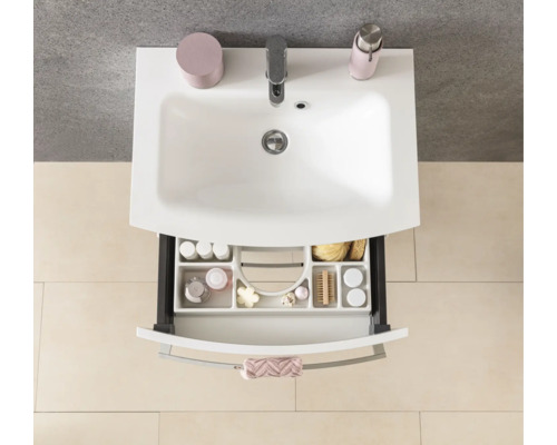 Vue de dessus d'un lavabo blanc avec robinet et un tiroir ouvert avec un organisateur clair pour les accessoires de salle de bains.