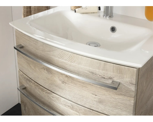 Meuble sous-vasque avec lavabo en céramique et deux tiroirs aspect chêne avec poignées en métal.