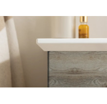Gros plan d'un meuble sous-lavabo avec décor en bois et un lavabo blanc.