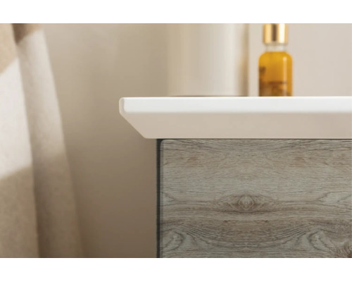 Gros plan d'un meuble sous-lavabo avec décor en bois et un lavabo blanc.