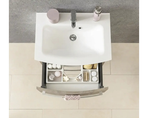 Meuble sous-lavabo aspect bois avec vasque blanche et tiroir ouvert avec aménagement, vue de dessus.