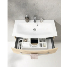 Meuble sous-vasque galbé aspect bois avec vasque en céramique blanche, robinet et tiroir ouvert avec organiseur.