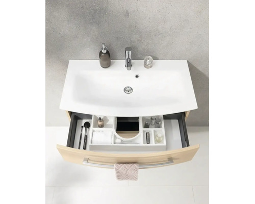 Meuble sous-vasque galbé aspect bois avec vasque en céramique blanche, robinet et tiroir ouvert avec organiseur.