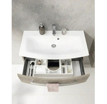 Salle de bain lumineuse et organisée avec meuble sous-vasque moderne, vasque en céramique blanche et tiroir ouvert avec système de rangement.