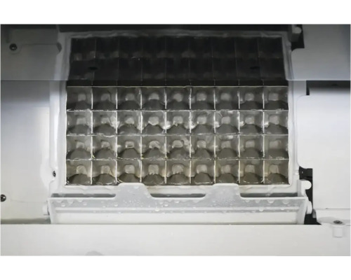 Innenansicht eines Eiswürfelbereiters mit einem Gitter aus Metall zur Herstellung von Eiswürfeln.