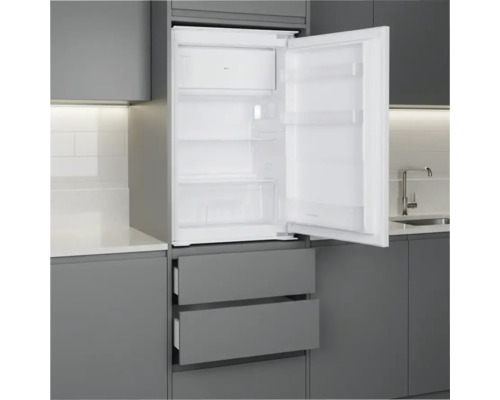Einbaukühlschrank mit Gefrierfach, geöffnet in einer grauen Einbauküche mit Glasablagen und Gemüseschublade.