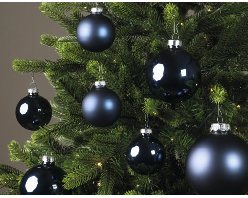 Blaue Weihnachtskugeln in verschiedenen Größen, teils matt und teils glänzend, an einem grünen Weihnachtsbaum.
