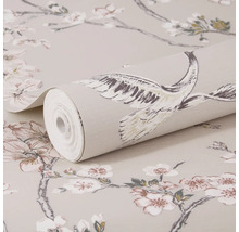 Papier peint intissé avec des branches de cerisier en fleurs et des grues, un rouleau posé sur le papier peint étalé.