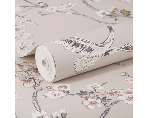 Papier peint intissé avec des branches de cerisier en fleurs et des grues, un rouleau posé sur le papier peint étalé.