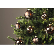 Braune Christbaumkugeln mit weissem Sternenmuster an einem geschmückten Weihnachtsbaum mit Beleuchtung.