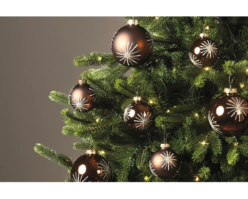 Braune Christbaumkugeln mit weissem Sternenmuster an einem geschmückten Weihnachtsbaum mit Beleuchtung.