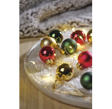 Festliches Arrangement aus Weihnachtskugeln in Rot, Grün und Gold auf einem Tablett mit Kunstschnee und LED-Lichterkette.