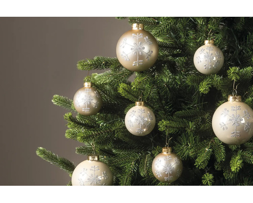 Weihnachtskugeln mit glitzerndem Schneeflocken-Muster an den Zweigen eines Tannenbaums.