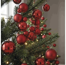 Rote Christbaumkugeln in verschiedenen Größen mit matter und glänzender Oberfläche an einem Weihnachtsbaum.