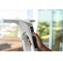 Main utilisant un nettoyeur de vitres blanc avec indicateur d'état de la batterie.