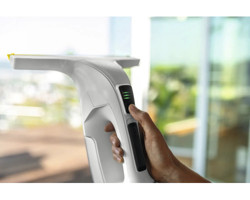 Main utilisant un nettoyeur de vitres blanc avec indicateur d'état de la batterie.