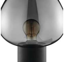 Lampe de table moderne avec abat-jour en verre et ampoule visible sur un socle rond simple.