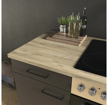 Plan de travail de cuisine moderne en aspect chêne clair sur un meuble bas sombre à côté d'une plaque de cuisson, avec planches à découper.