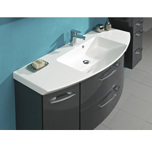 Meuble de salle de bain avec vasque blanche, mitigeur chromé et meuble bas gris foncé brillant avec façade incurvée.