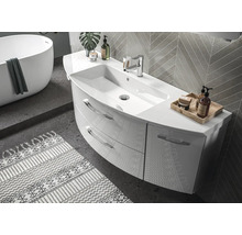 Salle de bains moderne avec meuble incurvé, deux tiroirs et robinetterie. Baignoire îlot et carrelage mural en arrière-plan.