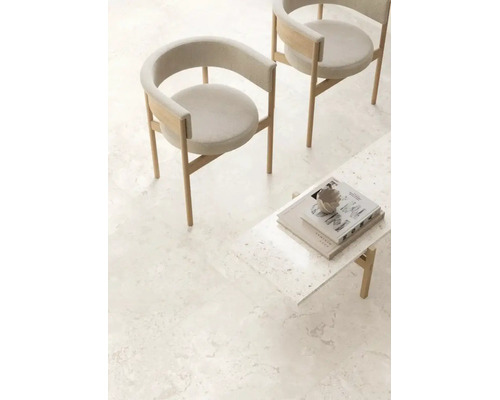 Heller Wohnraum mit Bodenfliesen in Natursteinoptik, zwei modernen Holzsesseln mit Polsterung und einem Beistelltisch.